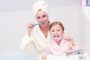 mother and daughter brushing teeth together