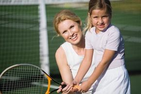 Woman teaching young girl tennis.