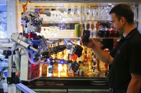 Mechatronics engineer Ben Schaefer interacts with humanoid robot bartender Carl as it prepares a drink at the Robots Bar and Lounge in Germany on July 26, 2013. Developed by Schaefer, Carl also can interact with customers in small conversations.