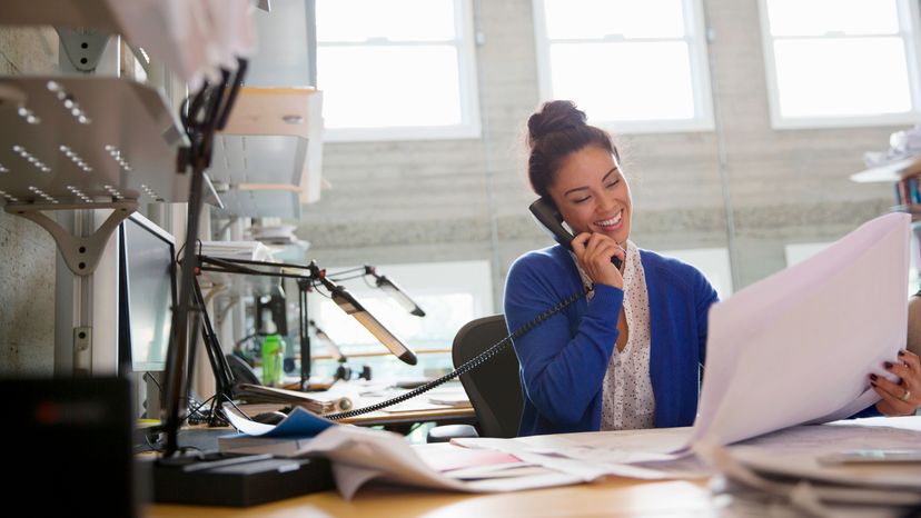 A woman on office talking through a landline telephone.