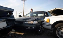 A man on his cell phone next to a three-car pileup.