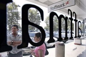 Job applicants converse outside the Staffmark temp agency in Cypress, Calif.