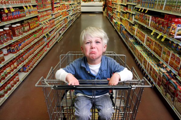 A toddler cries in a shopping cart.