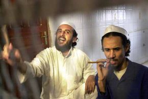贾马尔穆罕默德al-Bedawi(左)在狱中呼喊和法赫德al-Quso (R)看起来在他们听到判决结果在也门的审判结束时的六名武装分子被控2000年10月的轰炸的海军驱逐舰科尔。”border=