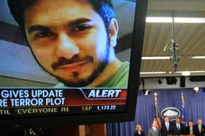 An image of terror suspect Faisal Shahzad flashes on a TV screen as U.S. Attorney-General Eric Holder (C) and other officials hold a briefing regarding the investigation into the Times Square attempted bombing.