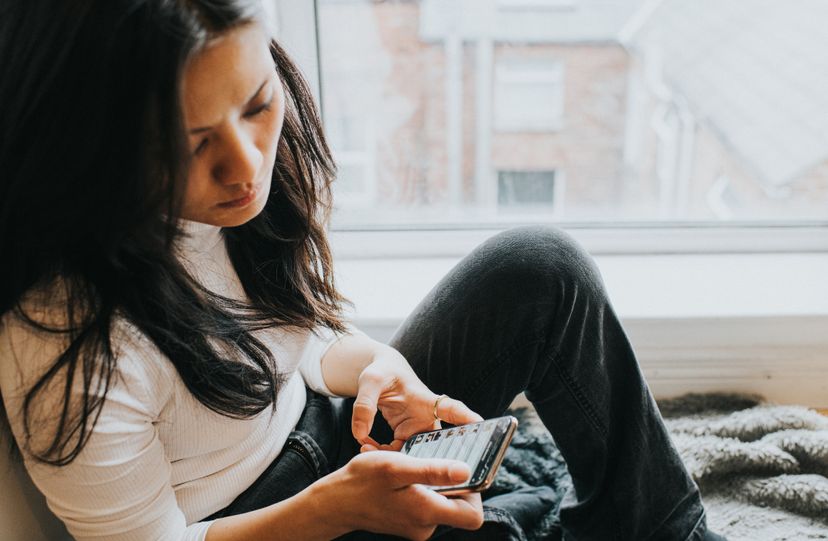 An elevated view of a concerned looking woman looking down at her mobile phone device.