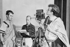Movie director David Bradley, in costume as Brutus, checks the camera angle for a shot of Grosvenor Glenn, playing Cassius, as assistant director Thomas A. Blair checks the script during filming of the 1950 movie 'Julius Caesar.'
