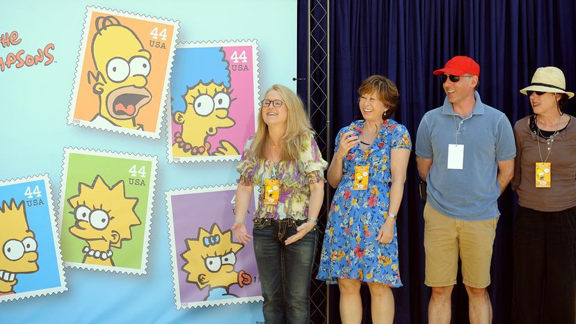 Nancy Cartwright, Yeardley Smith, dan Castellaneta and Julie Kavner (L-R), voice actors on the show, pose by stamps featuring Simpsons characters. GABRIEL BOUYS/AFP/Getty Images