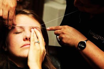 A woman has her eyebrows threaded at a fashion show in London.