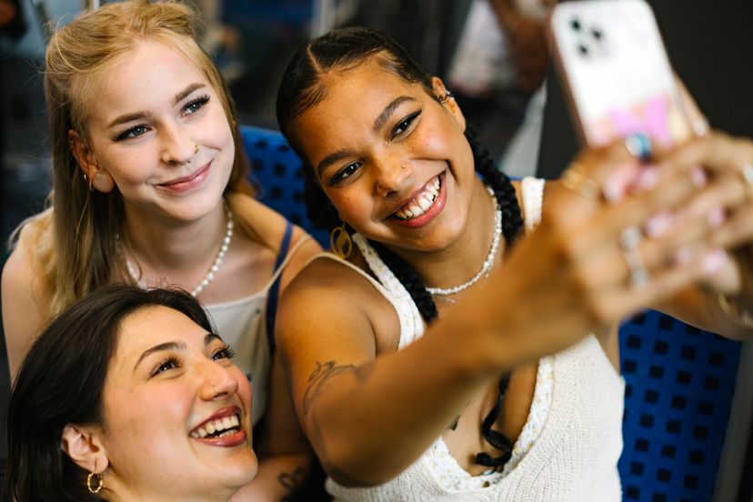 Three young woman generation z taking a picture togehter with their phone and smiling into the camera