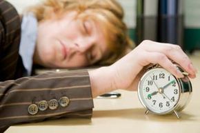 Woman falling asleep at alarm clock.