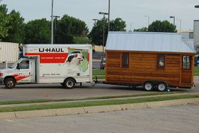 A U-Haul van tows a tiny house to its next destination. Tiny houses don't tow as easily as RVs.