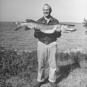 Smiling, old-fashioned person outdoors in black and white.