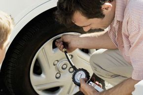 Man checking tire pressure with gauge.&nbsp;