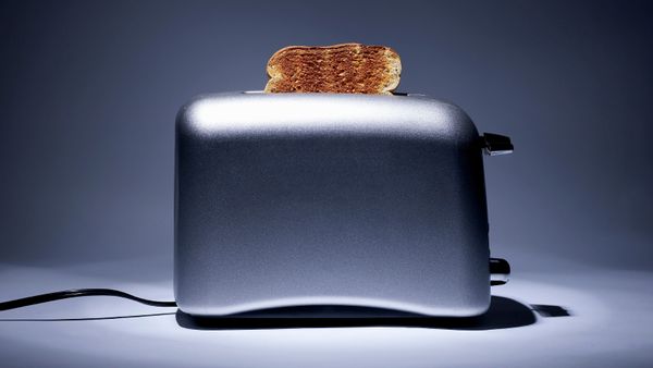Silver colored toaster with single slice of toast