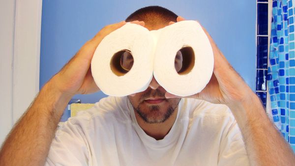 Man holding toilet paper as binoculars