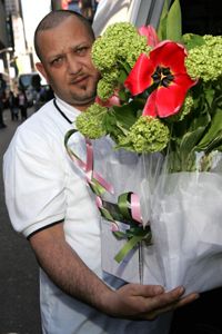 Delivery man holding a bouquet of flowers on a sidewalk.