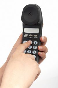 Hand pressing numbers on a telephone or cell phone.