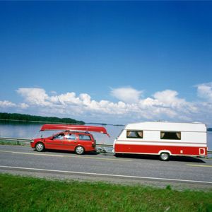 A car carrying a canoe and pulling a trailer