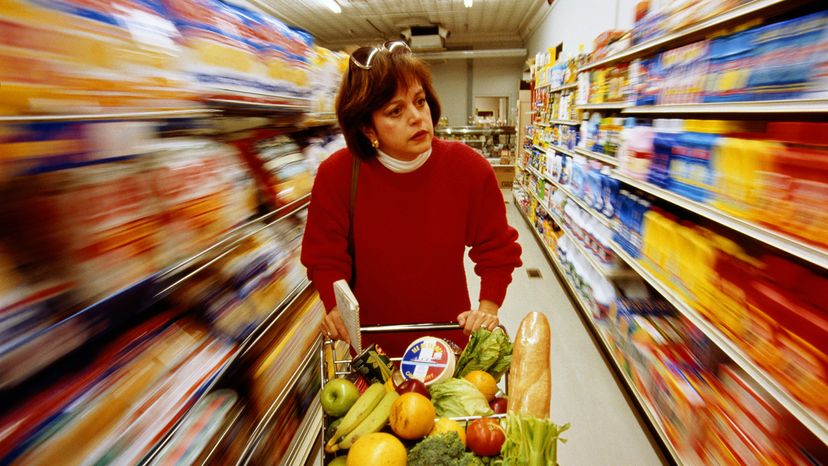 Woman pushing shopping card with aisles blurred