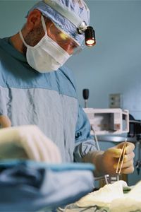 Surgeon in operating room holding tweezers