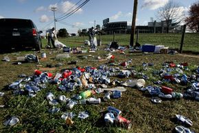 Alvin Peachy, background left, and Sam Estright clean up fields used for parking and tailgating in the shadow of the Penn State Nittany Lions' Beaver stadium.