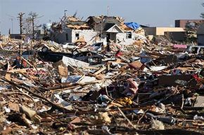 人们调查了2013年11月18日在伊利诺伊州华盛顿的龙卷风之后的一个细分中的损害。“width=