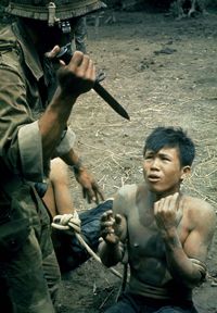 A Vietnamese paratrooper threatens a suspected Viet Cong soldier with a bayonet during an interrogation in 1962.