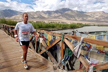 Person stands alone atop a mountain outdoors.