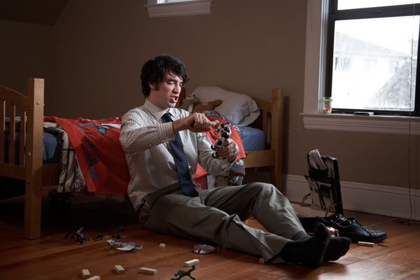 Toy tester sitting on floor playing with toys in bedroom.