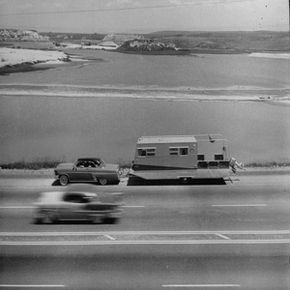 Trailer being towed by car on highway.