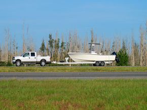 Pick-up truck tows boat on the road. 