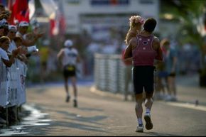 A triathlete races with his young daughter during the 1998 Ironman triathlon in Hawaii. Families traveling to triathlons don’t have to get this involved unless they want to.