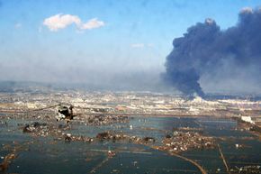 海啸和地震破坏的鸟瞰图,从日本北部海岸的美国海军直升机在3月12日,2011年。”border=