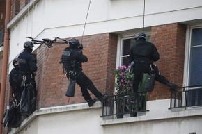 Members of a French police intervention unit take positions while a drone flies outside a building where a man is barricaded with his children and threatening their safety.