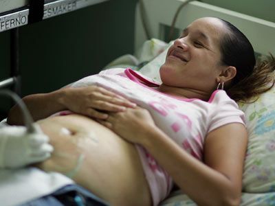Enedino Ortega, four months pregnant, lies on a bed as Zaditza Silveira uses an ultrasound machine to take images of her baby at the Birthing Center of South Florida.
