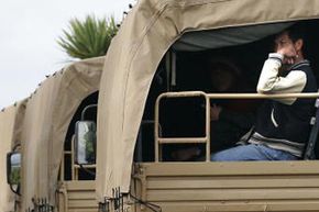 People wait in army unimog vehicles after being evacuated from the Papamoa Village Park camp ground, south east of Tauranga in the Bay of Plenty, New Zealand, following extensive flooding.