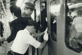 An oshiya (pusher) is needed to cram passengers into a commuter train during rush hour in crowded Tokyo, as seen in this 1987 photo.