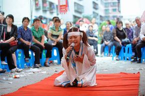 专业哀悼者胡Xinglian行动在葬礼上在重庆,中国。她与一个完整的soundsystem,多色聚光灯和她带的六名成员。”border=