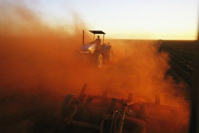Farm equipment harvesting in dusty outdoors agriculture.