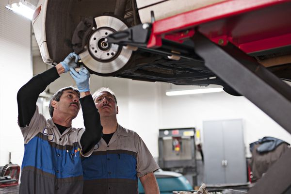 Mechanics working on car in shop