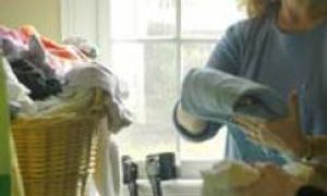 woman with arm crutches folding laundry