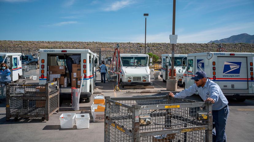 mail carrier pushes a cart out of a United States Postal Service sorting facility