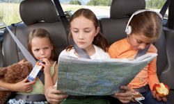 A young girl reads a map in the back seat of a car.