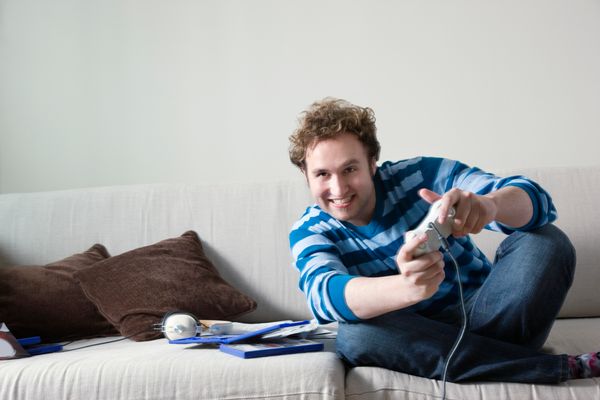 Man using computer game controls sitting on sofa.
