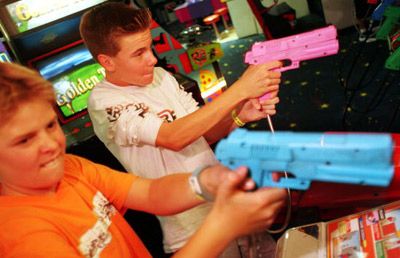 Two teen boys play at an arcade. 