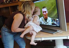 Autumn Lewis, 19 months old, gets a lift so she can kiss dad, Corporal Barry Lewis, in Iraq.