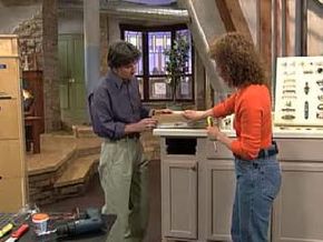 A man and a woman building kitchen cabinets.&nbsp;