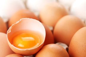 brown eggs with one cracked open to expose yolk and egg white