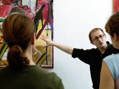 Man pointing at painting on wall in front of people